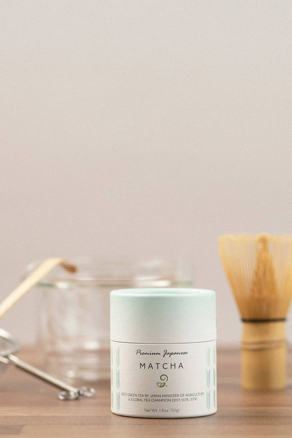 Matcha powder container with tea-making tools on a wooden surface